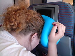 Woman demonstrating the "forward-facing seat" brace position by cradling the head on the seat in front. Brace position.jpg