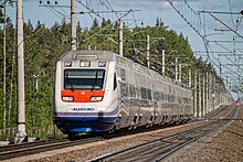 Train blanc photographié de devant sur une ligne ferroviaire électrifiée.