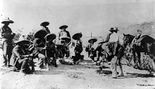 A group of 14 armed men, eight of them crouching down, in sombreros and holding rifles