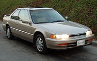 Front three-quarter view of a two-door car with a three-box body style fitted with a sunroof and rear spoiler.