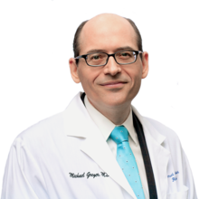 Photograph of Michael Greger in a white coat and brightly colored tie with a transparent background
