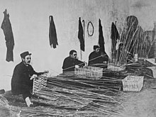 Black and white photo of three men weaving wicker baskets