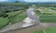 An aerial drone view of the Acelhuate River emptying into the Lempa River, with the Acelhuate River's water darker than that of the Lempa River