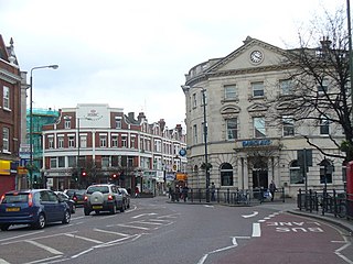 トゥイッケナム中心街、キング・ストリートの東端を占めるバークレイズ銀行と、傍らのHSBC (Central Twickenham The classical facade of Barclays Bank dominates the east end of King Street. Another bank, HSBC, is visible beside it.)