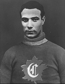 Half-length view of an ice hockey player in his late twenties. He has short black hair and a serious look. He is wearing a sweater with the letter C surrounded by a maple leaf on the chest.