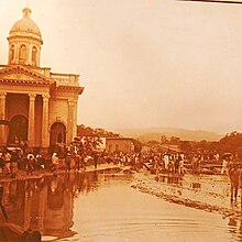 People navigating around a flooded street in San Salvador in front of a church