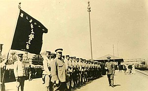 Sepia image of soldiers standing in formation for review, facing camera.