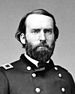 Head and shoulders of a white man with a full beard, wearing a double-breasted military jacket with a rectangular patch over each shoulder.