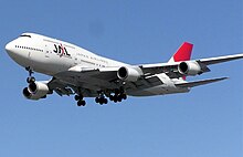 A Boeing 747-400 aircraft in mid-air, with blue sky in the background