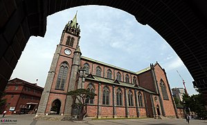 Photographie d'une église. Les murs sont constitués de briques rouges et noires.