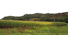 Steep hills loom over a cornfield.