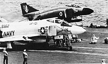 Two jet aeroplanes on catapults awaiting launch from an aircraft carrier