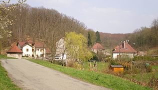 Groupe de maison au milieu de collines boisées.