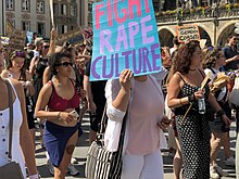 Demonstrierende Person trägt Schild mit der Aufschrift "Fight Rape Culture".