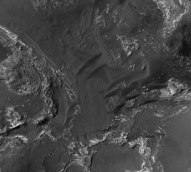 Orson Welles Crater, as seen by HiRISE. Layered, light-toned rocks seem to be under a dark mantling material. Layers may be sandstone, volcanic ash, or lakebed deposits.