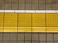 Tactile pavings installed on a platform at a Japanese train station. Horizontal tactile paving at the bottom indicates the 'inner' side, away from the rail tracks.