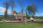 Wooden church with a small spire, surrounded by trees