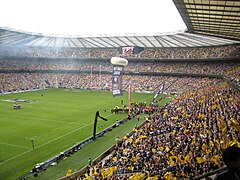 plan large d'un stade rempli de supporters aux couleurs noires et jaunes.