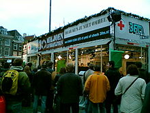 Glass building, with signs on top and spectators outside