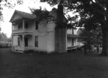 A black and white image of the James Dickson house, an early 19th century two story farm house with a pitched roof and front porch.