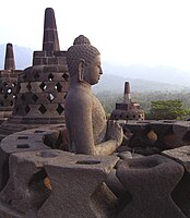 At Borobudor hundreds of Buddha statues sit inside openwork stupas; here the nearest is partly deconstructed