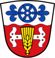 Gemeinde Saaldorf-Surheim Im Wellenschnitt geteilt von Silber und Rot, oben ein blaues Rad, das rechts und links mit einer wachsenden blauen heraldischen Lilie besteckt ist, unten ein waagrechtes silbernes Türband, überdeckt von einer goldenen Ähre.