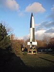 Réplique du premier prototype de V2 tiré avec succès en octobre 1942 photographiée en 2002 au musée de Peenemünde. Comme l'original, sur l'empennage du missile se trouve un dessin rendant « hommage de façon humoristique au film »[29] La Femme sur la Lune de Fritz Lang (1929). La peinture en damier noir et blanc permettait « d'analyser les mouvements de la fusée lors du dépouillement des films réalisé pendant le vol »