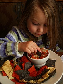 A young girl eating tortilla chips with pico de gallo A girl enjoying Pico de Gallo for the first time.jpg