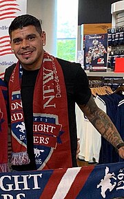 A middle-aged man who is wearing a "Midnight Riders" scarf is smiling while holding a banner.