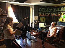 A person reads from a book in the studio at KZCT (OZCAT) radio in Vallejo, California. KZCT radio.jpg