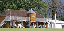 Cricket pavilion with players watching on a summers day