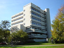 Bâtiment moderne en L, dans un parc.