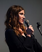 Kathryn Hahn facing to the right holding a microphone