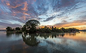 Colorful clouds and blue sky with water reflection of an island hosting trees at sunrise in Si Phan Don, Laos