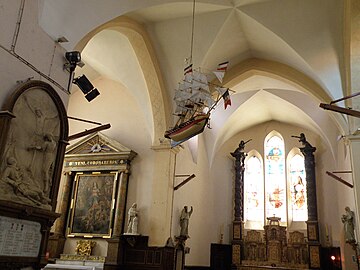 Intérieur de l'église : le bateau suspendu à la voûte de la nef et, à droite, le chœur avec son retable entre deux colonnes torsadées.