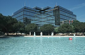 Photographie du quartier Mériadeck. En avant plan, une fontaine d'eau bleu cristal. En arrière plan, un bâtiment de plusieurs étages moderne en verre.