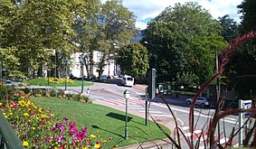 Photographie du centre d'une ville avec une route et des espaces verts.