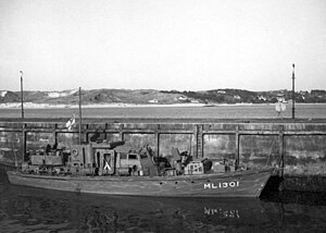 Black and white image of a Harbour Defence Motor Launch tied up alongside a quay