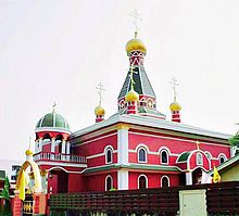 A red, green, and yellow cathedral with Byzantine crosses erected at its highest points