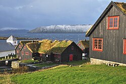 Saint Olav's Church, Kirkjubøur at the left, and the old farmhouse of Kirkjubøargarður at the centre. In the background are the islands of Sandoy and Hestur.