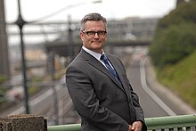 Photograph of a man wearing a suit and glasses