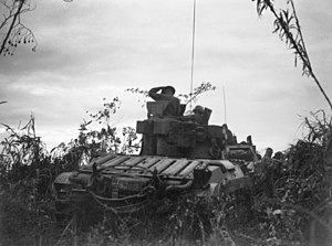 An armoured vehicle moves through thick vegetation