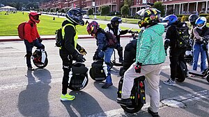 EUC and motorized scooter riders participating in a group ride in San Francisco. PPE was worn due to higher top speed with newer EUC models. The man in a red jacket on the left was riding a suspension-model. Euc presidio.jpg