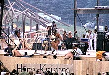 Richie Havens, seated onstage, singing and playing an acoustic guitar