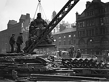 A crane lifts a large statue into the air.