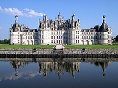 Photographie couleur de face d'un château de style Renaissance, précédé de douves et d'une pelouse.