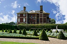 A photograph of the east side of the house taken from the Cherry Garden, which is notable for its formally-landscaped pattern including conical firs