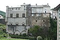 photo couleur d'une bâtisse fortifiée construite en pierres gris clair et gris sombre. La couverture est d'ardoise gris anthracite.