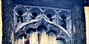 Close up of the top of a second floor window, which is made of old oak wood, cut into an arch with multiple semi circular foils