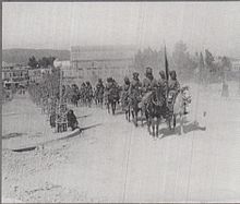A photograph showing a regiment of Indian cavalry riding their horses in a column through Damascus